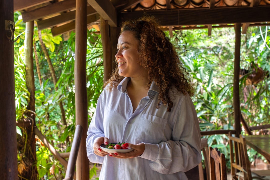 A smiling woman holding berries on a tropical porch.